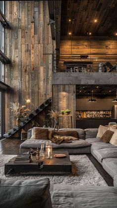 a living room filled with lots of furniture next to a tall wooden wall covered in windows