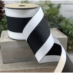 black and white striped ribbon on wooden box with pine cones in background, closeup