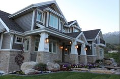 the front of a house with stone and stucco sidings, windows, and landscaping