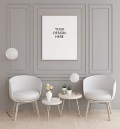 two white chairs and a table in front of a gray wall with a poster on it