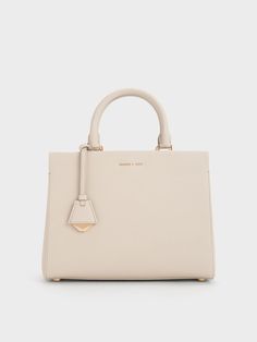 This product is made with at least 20% sustainable materials by weight. CHARLES & KEITH uses recycled, degradable, organic, and water-based materials in our eco-conscious collection.You can never go wrong with a classy carrier in a versatile shade, and this iteration of the Mirabelle bag is exactly that. The creamy ivory finish and structured silhouette makes clean lines the focal point, with a luxurious gold-accent bag charm to add shine. Maximising functionality, the roomy interior comes with Charles And Keith Bags, Charles And Keith, Structured Top, Classic Handbags, Luxury Purses, Charles Keith, Gold Accent, Quilted Bag, Handle Bag