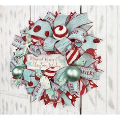 a christmas wreath hanging on the side of a white door with red and blue decorations