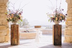 two vases filled with flowers sitting next to each other on top of a stone floor