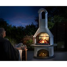 a man sitting in front of an outdoor fireplace