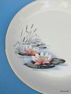 a plate with water lilies and reeds painted on the side, against a blue background