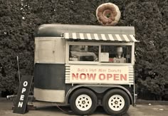 a donut truck is parked in front of some trees