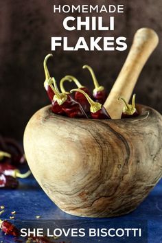 a wooden bowl filled with chili flakes on top of a blue tablecloth next to a