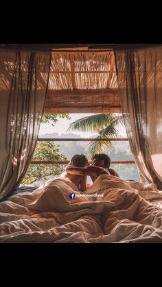 two people are laying in bed with their backs to each other and looking out the window