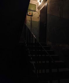 the stairs leading up to an open door in a dark room with lights on them