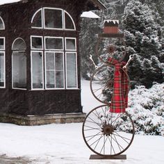 an old fashioned bicycle in front of a house with snow on the ground and trees