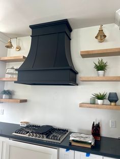 a black stove top oven sitting in a kitchen next to shelves filled with potted plants