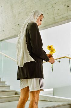 a man with a flower in his hand is walking down the stairs and looking at something