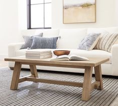 a living room with a white couch and wooden coffee table in front of a window