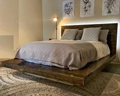 a bed sitting on top of a wooden platform next to a wall with pictures above it