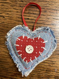 a heart shaped ornament with a button in the center on a wooden table