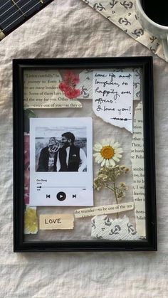 an old photo frame with flowers and pictures on it next to a cup of coffee