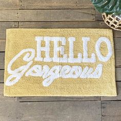 a yellow door mat that says hello gorgeous on it next to a potted plant