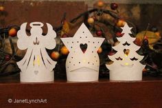 three paper christmas trees sitting on top of a wooden shelf