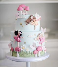 a three tiered cake with fairy figurines on it's sides and mushrooms