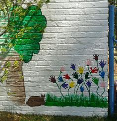 a brick wall painted with flowers and a tree