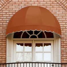 an orange awning on top of a brick building next to a white door and window