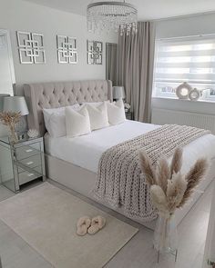 a bedroom with a white bed, chandelier and pillows on the headboard