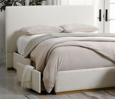 a bed with white linens and pillows in a room