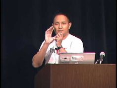 a man standing at a podium with his hands up in front of him and speaking into a microphone