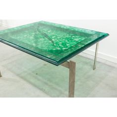 a green glass table with metal legs