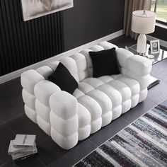 a white couch sitting on top of a hard wood floor next to a lamp and rug