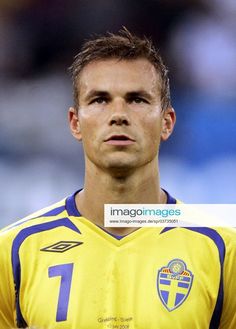 a soccer player in yellow and blue uniform looking off to the side with his head tilted