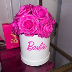 a white box with pink roses in it on a glass table next to a mirror