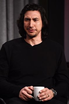 a man sitting in a chair holding a coffee cup