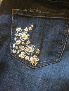 a pair of jeans with daisies embroidered on them