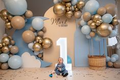 a baby is sitting on the floor in front of balloons