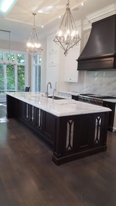 a large kitchen with an island in the middle and chandelier hanging from the ceiling