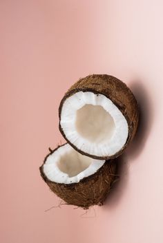 two halves of a coconut on a pink background