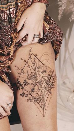 a woman's legs with tattoos on them and flowers in the middle of her thigh