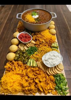 a platter filled with chips, dips and other foods on a wooden table