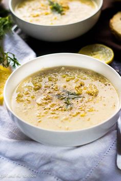 two white bowls filled with soup on top of a table next to lemon wedges