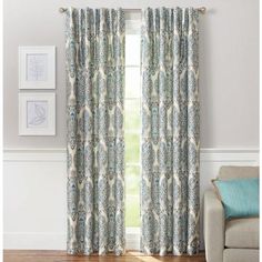 a living room with a couch, chair and window in front of the curtain that has an ornate pattern on it