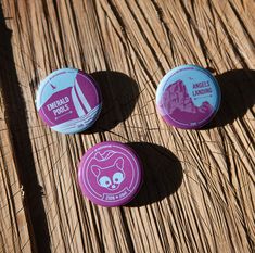 three pink and blue buttons sitting on top of a wooden table next to each other