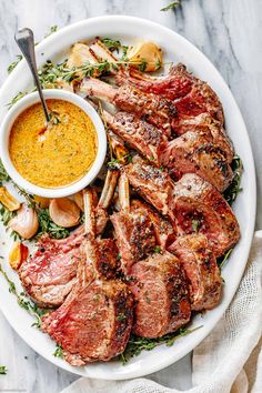 a white plate topped with meat and veggies next to a bowl of mustard