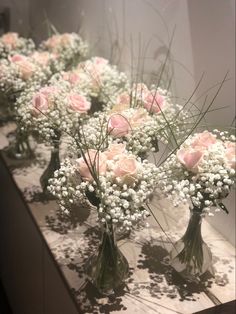 several vases filled with pink roses and baby's breath