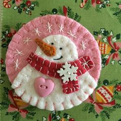 a pink and white snowman ornament on a green background