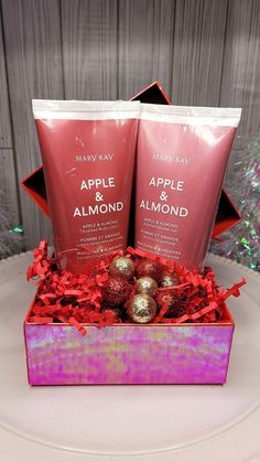 two bottles of apple and almond hand lotion in a pink box on a table