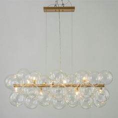 a chandelier with clear glass balls hanging from it's brass frame and wooden bar