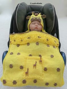 a baby in a car seat wearing a yellow blanket with giraffes on it