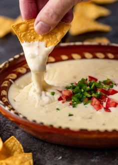 a tortilla chip being dipped into a bowl of quesadilla dip