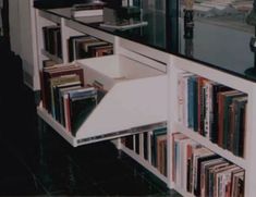 a book shelf filled with lots of books next to a counter top covered in cds